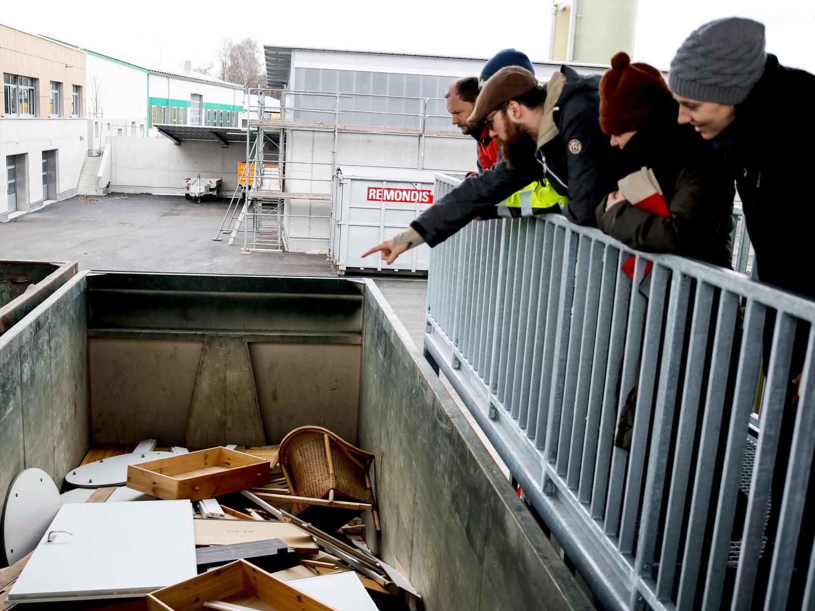 Eine Gruppe von Menschen schaut in einen Container voller Holz.