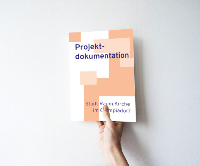 Eine Hand h&auml;lt eine Brosch&uuml;re mit dem Titel 'Projektdokumentation Stadt.Raum.Kirche im Olympiadorf' vor wei&szlig;er Wand